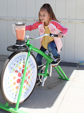 child smiling while riding a blender bike