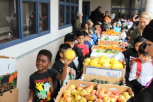 A group of students look at the WaveCrest Cafe Farm 2 School Farmers Market produce